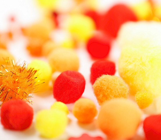 Close up photo of a red, orange, and yellow Crayon surrounded by scribbles on a white piece of a paper.