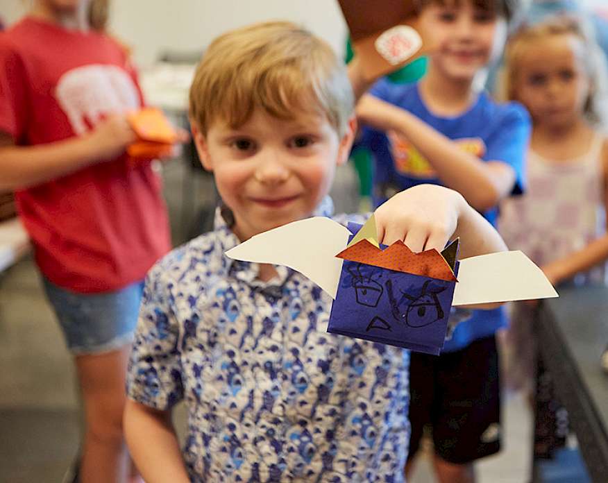 Photo of a young boy smiling and holding a handmade puppet.