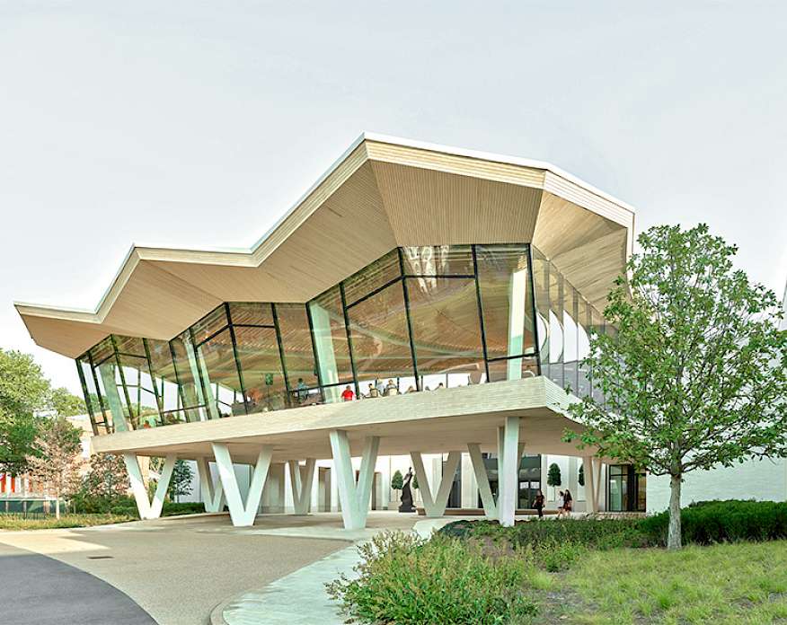 Photo of the Courtyard Entrance to the Arkansas Museum of Fine Arts. People are visible in the Cultural Living Room on the second floor.