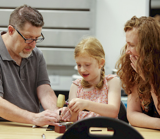 Photo of a man, woman, and young girl working on a metal art project in an art studio at the Windgate Art School